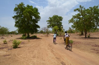 Das Bild zeigt Kinder auf Fahrrädern auf einer Straße in Ouidtenga am Rande von Ouagadougou.
